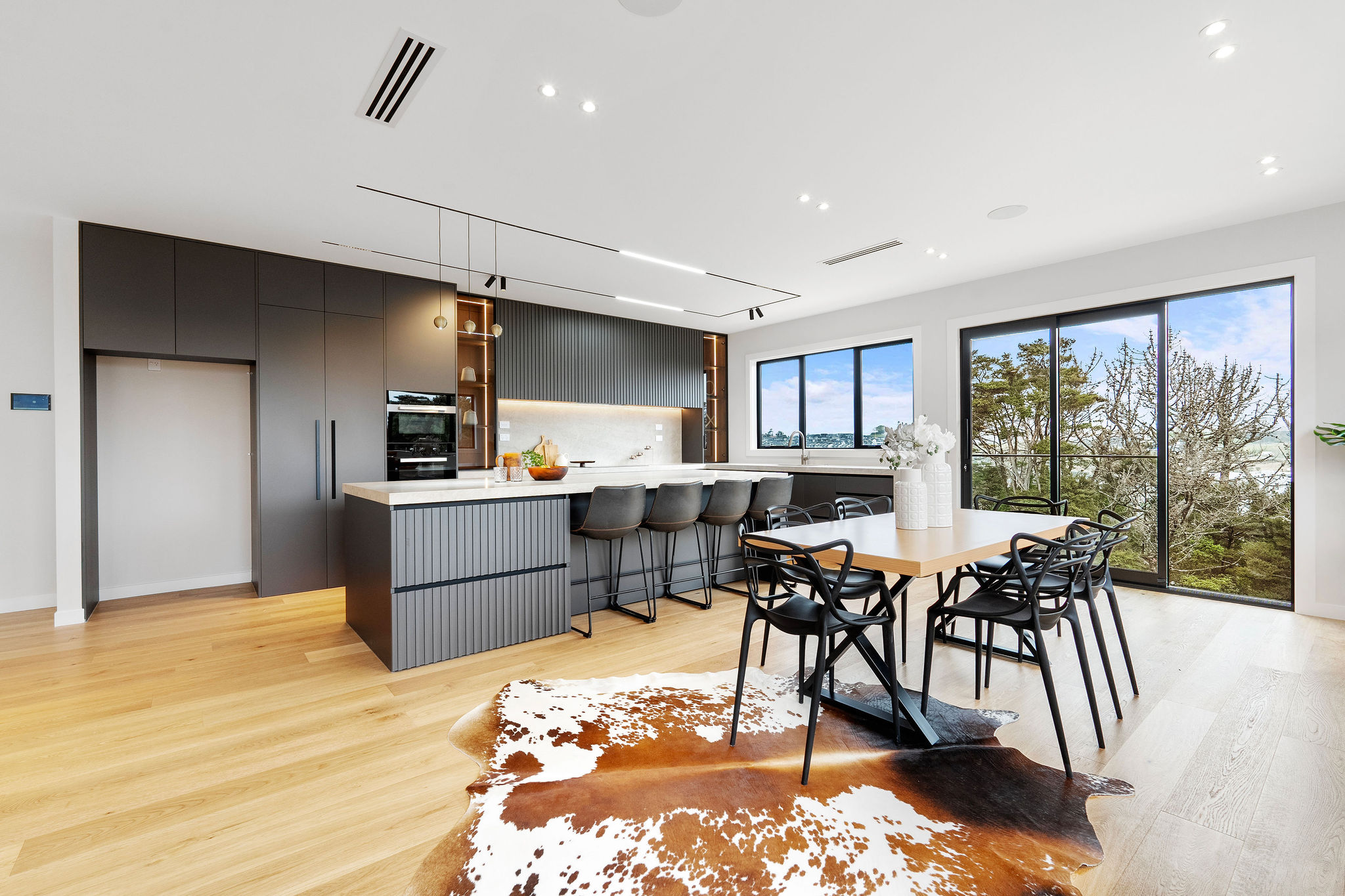 Kitchen island with dark joinery and warm timber floor