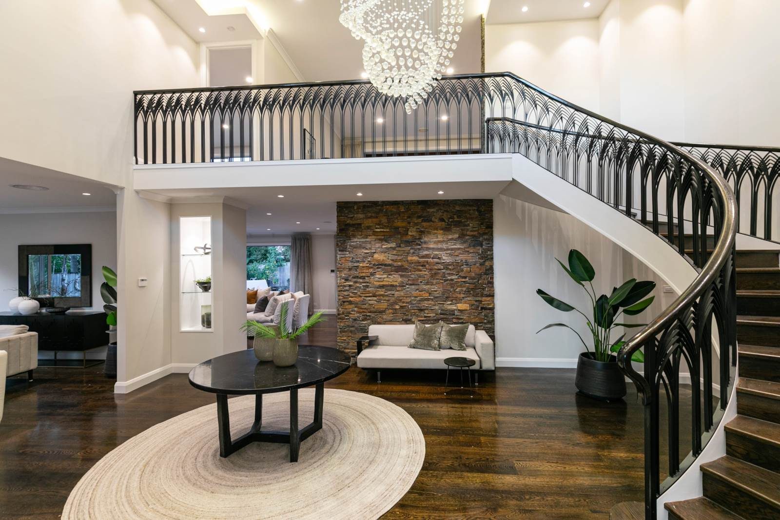 Double-height entry hall with stone wall and feature lighting