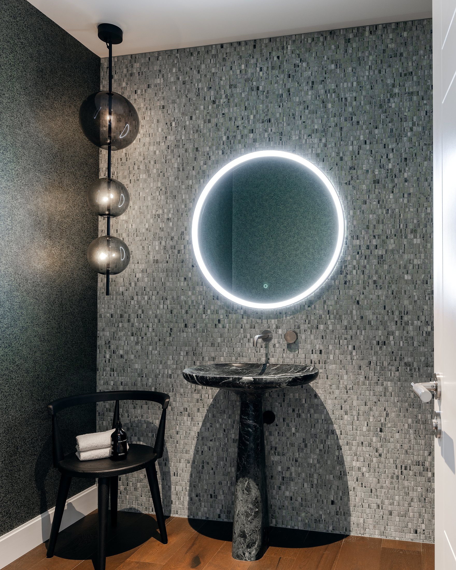 Bathroom with sculptural basin and dark material palette