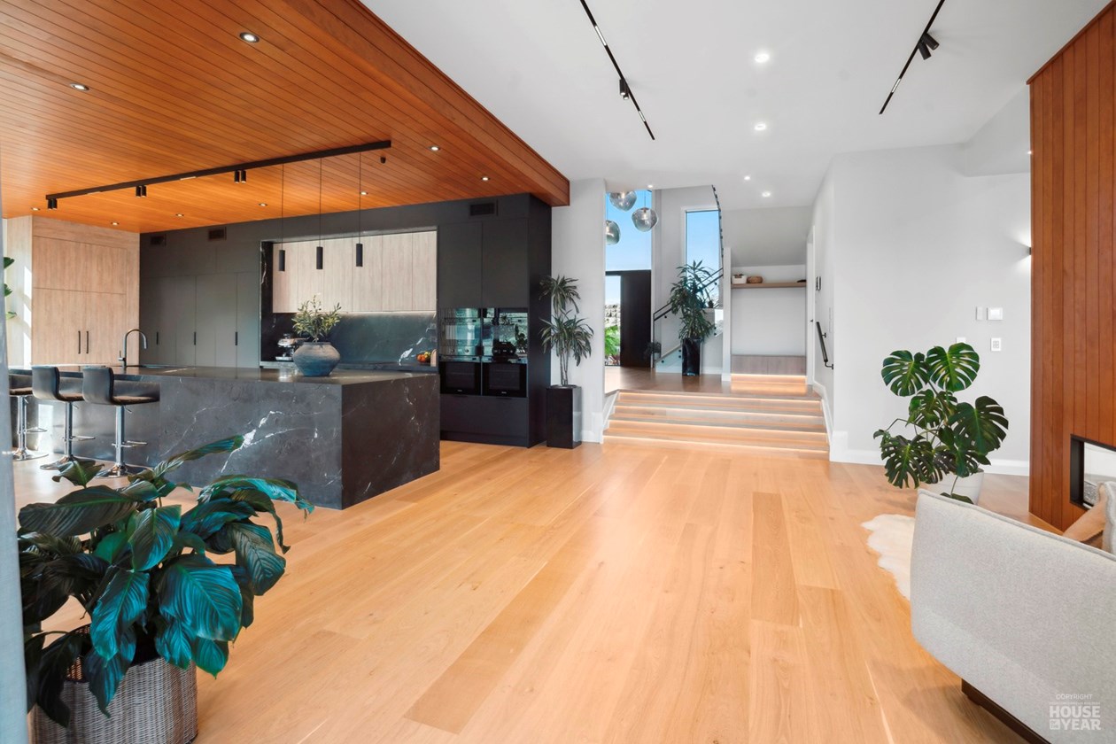 Kitchen island and light-filled hall with timber flooring
