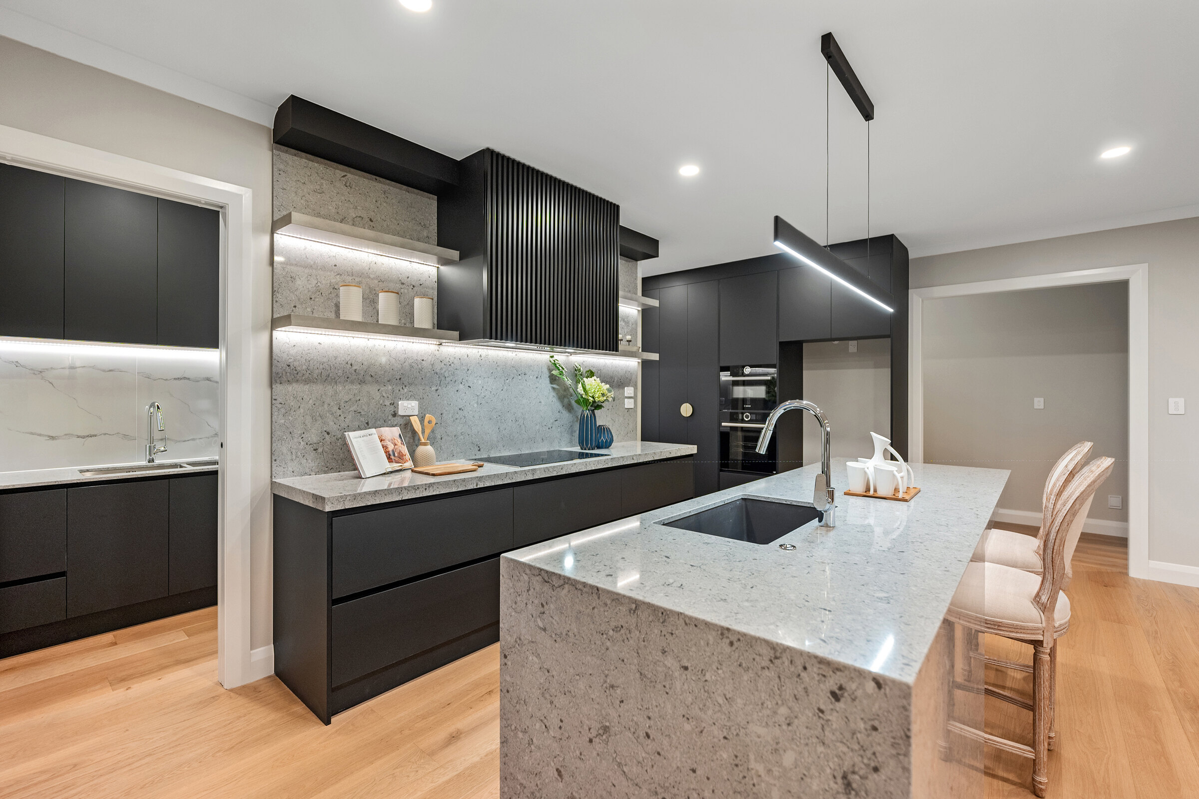 Kitchen with dark cabinetry, stone island and timber flooring at 56 Kewa Road
