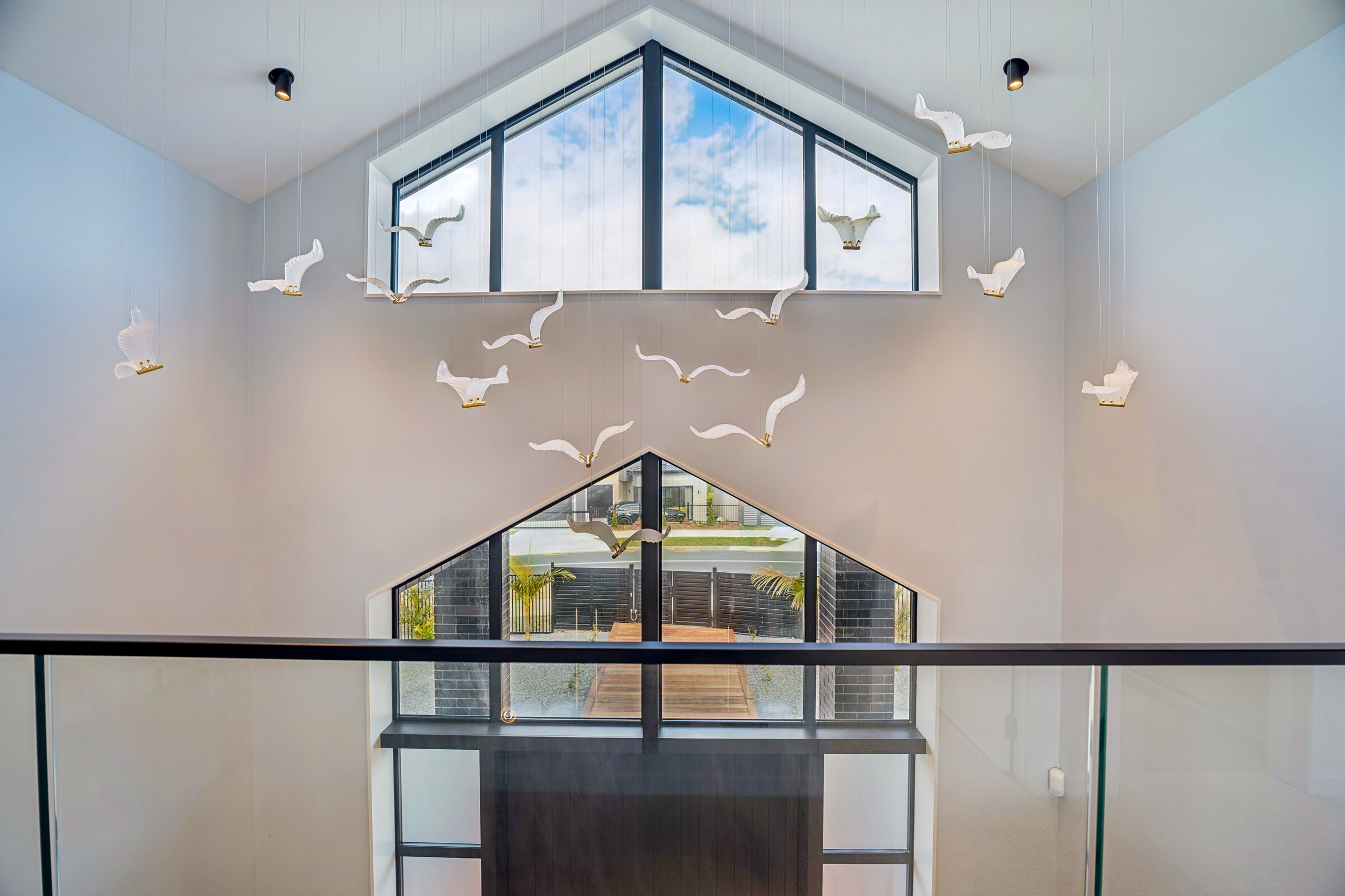 Double-height void with sculptural bird installation at 73 Kewa Road