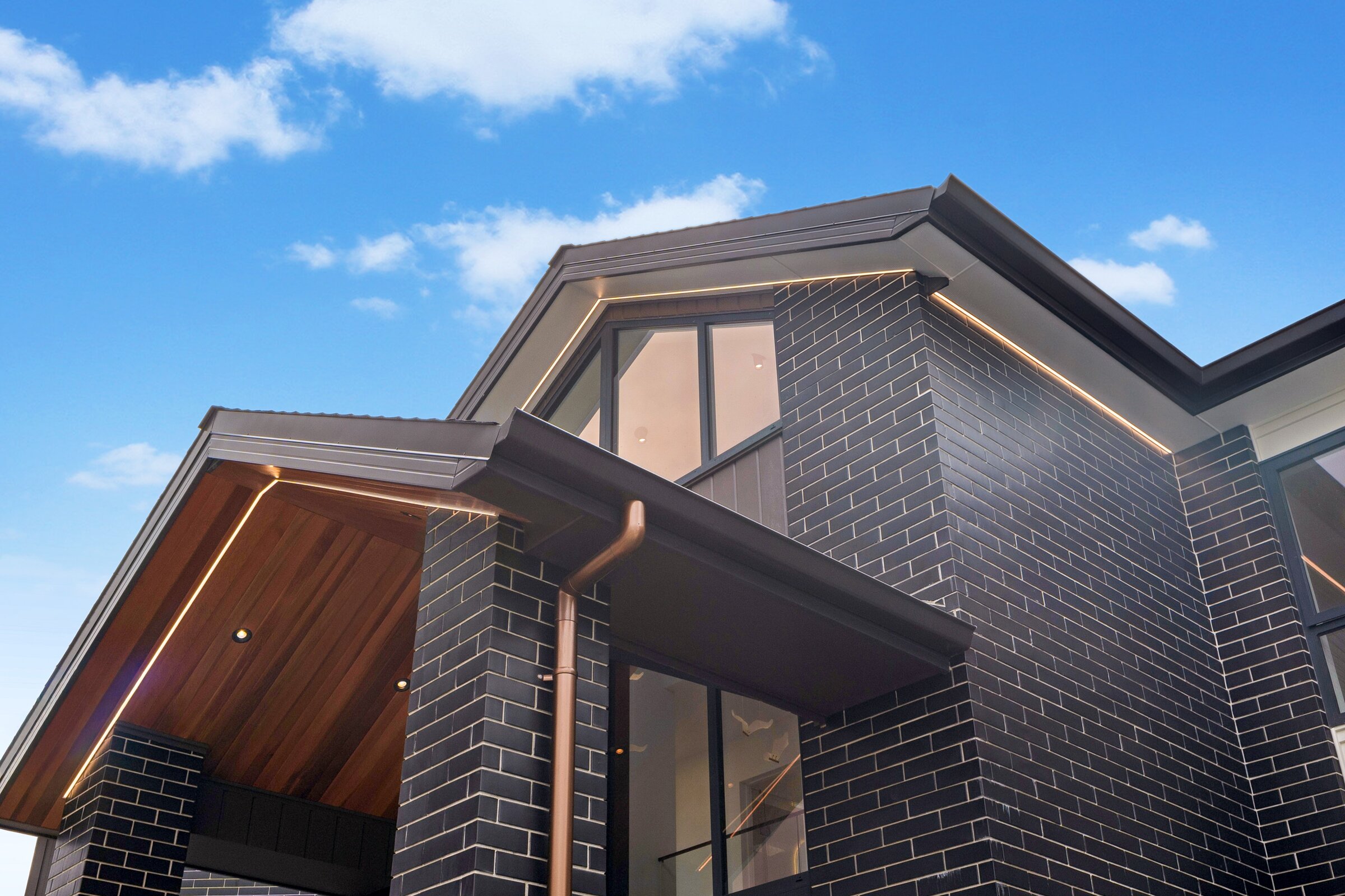 Exterior detail of dark brick, timber soffits and concealed lighting at 73 Kewa Road